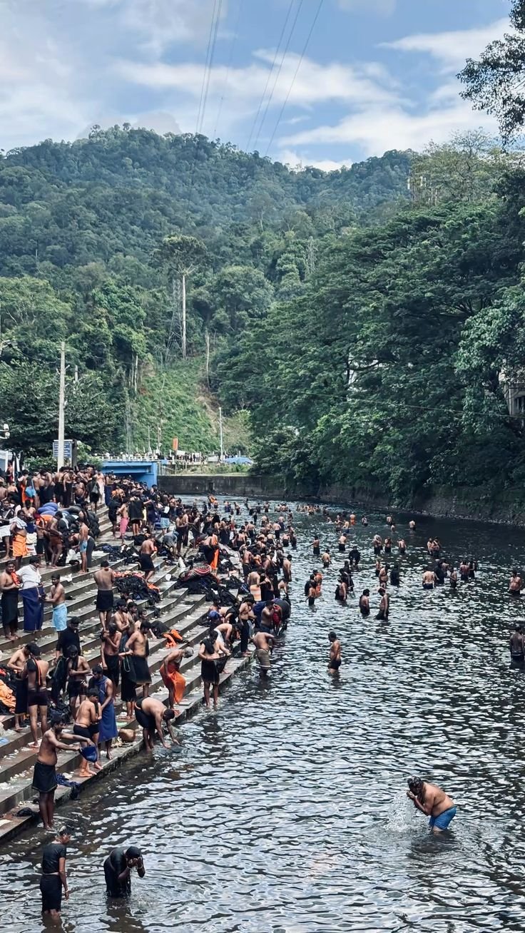 Pilgrims at the river ghat surrounded by forest